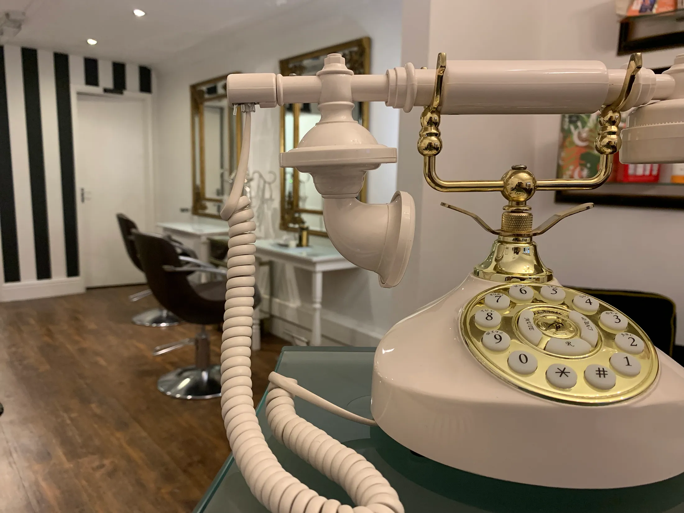 Inside Victoria's Hair Design — gilt mirrors, styling chairs and a cream and brass telephone at the front desk