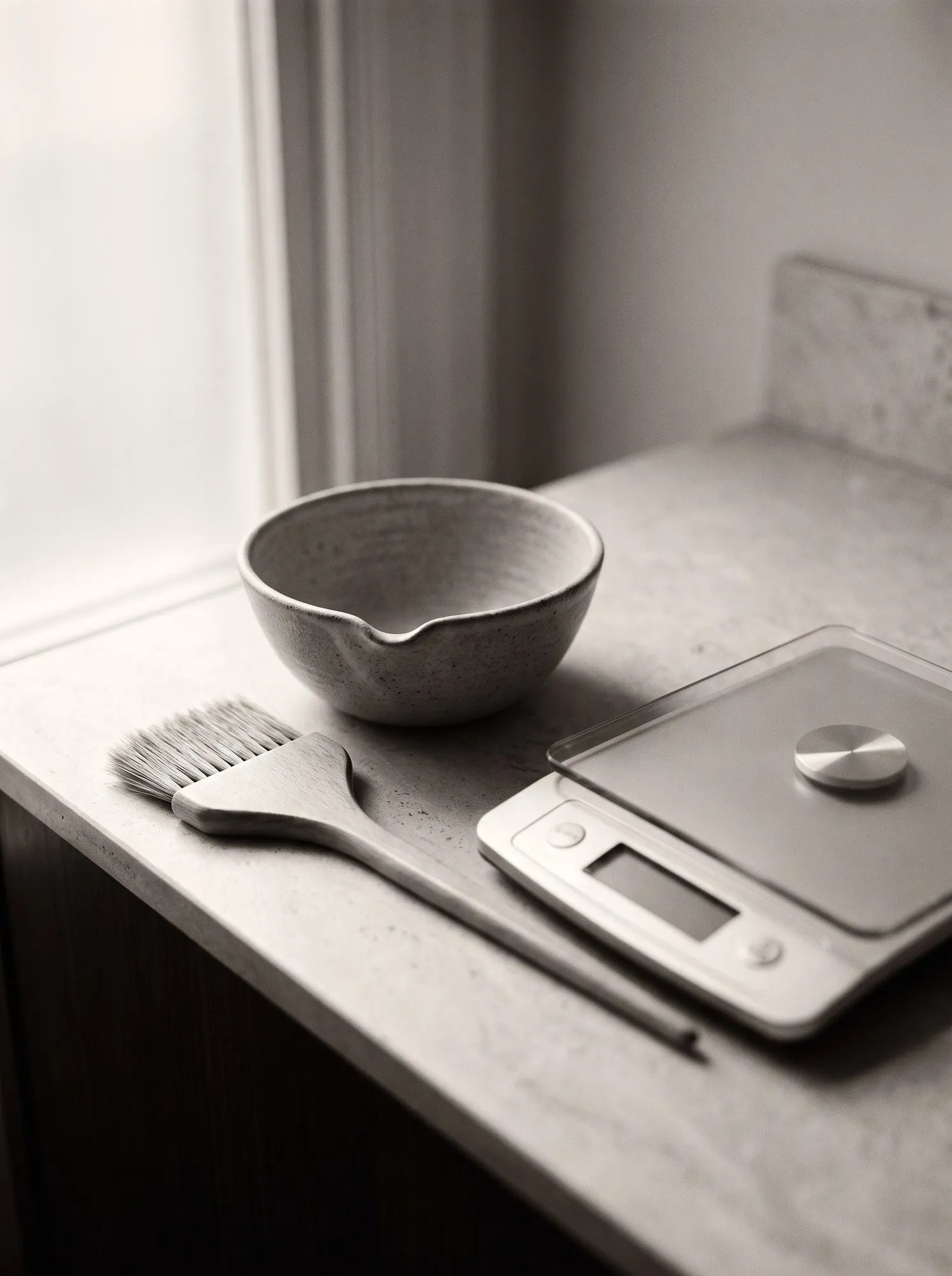 A tinting bowl, colour brush and a set of digital scales on a worktop